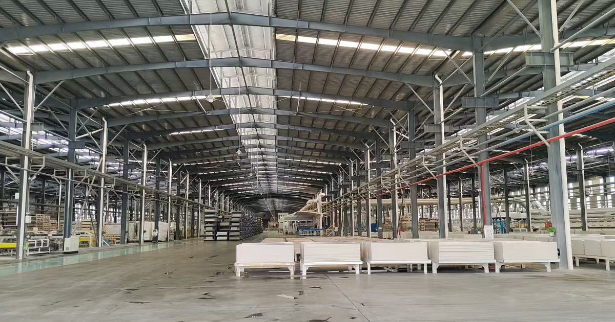 Wide view of an empty production hall at a Chinese factory, panel stacks on the floor