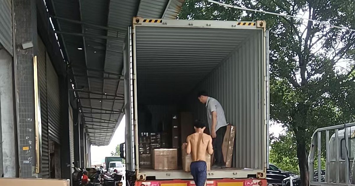 Workers stacking cartons inside a container at a loading bay in China