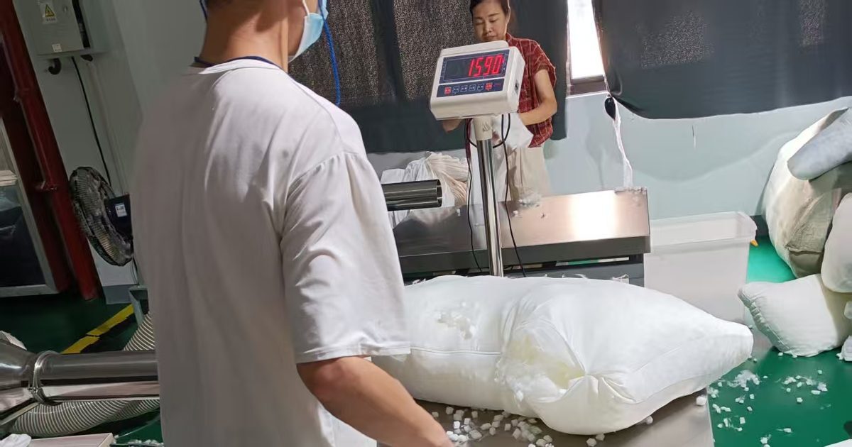Worker weighing pillow fill on a floor scale reading 1590 at a Chinese factory